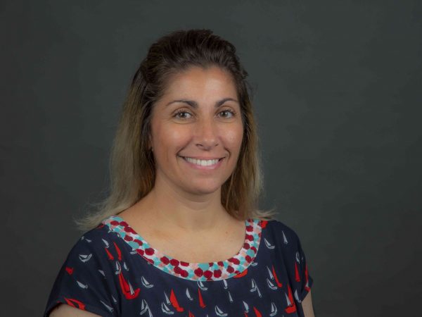 Woman smiles in front of gray background